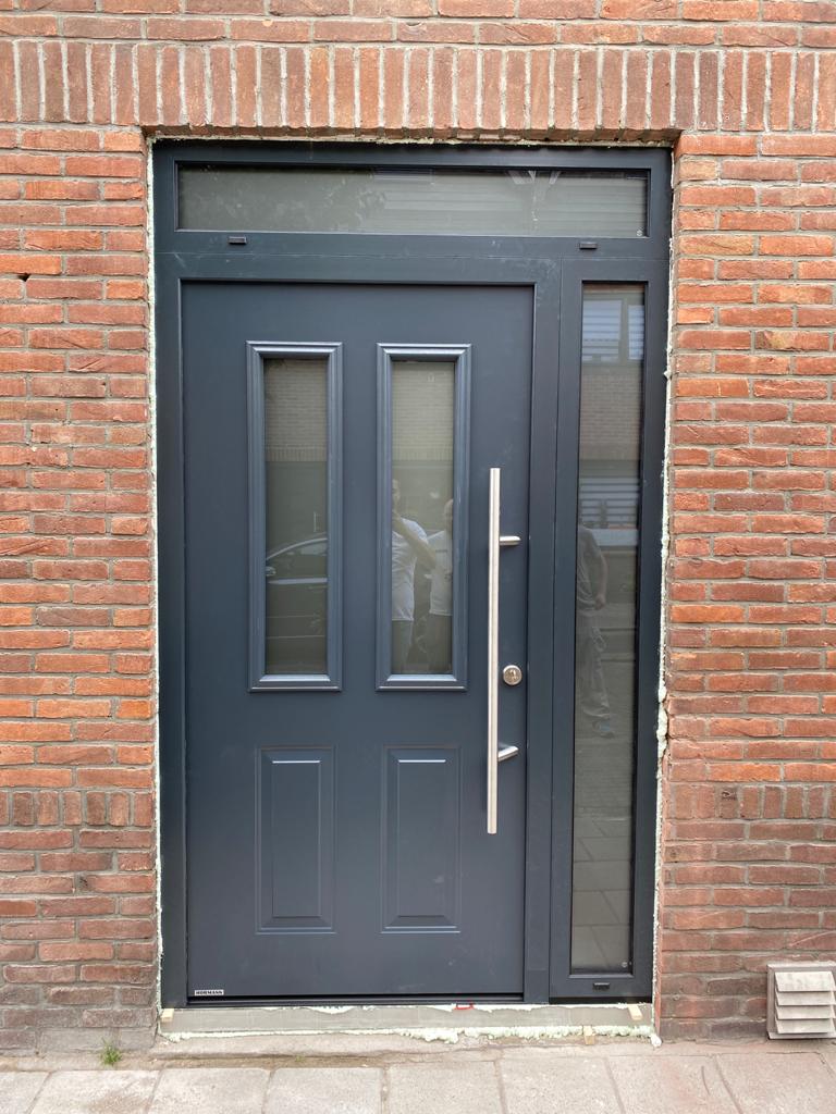 Antracietkleurige Hörmann voordeur met zijlicht, geplaatst in een gevel van rode baksteen