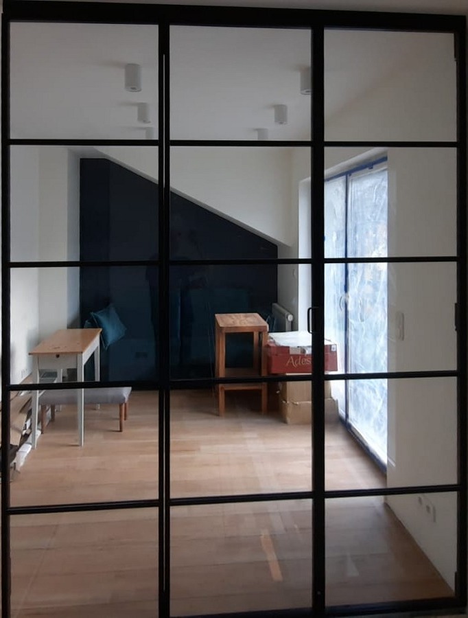 Glazen scheidingswand met zwart stalen-look frame in een nieuw appartement